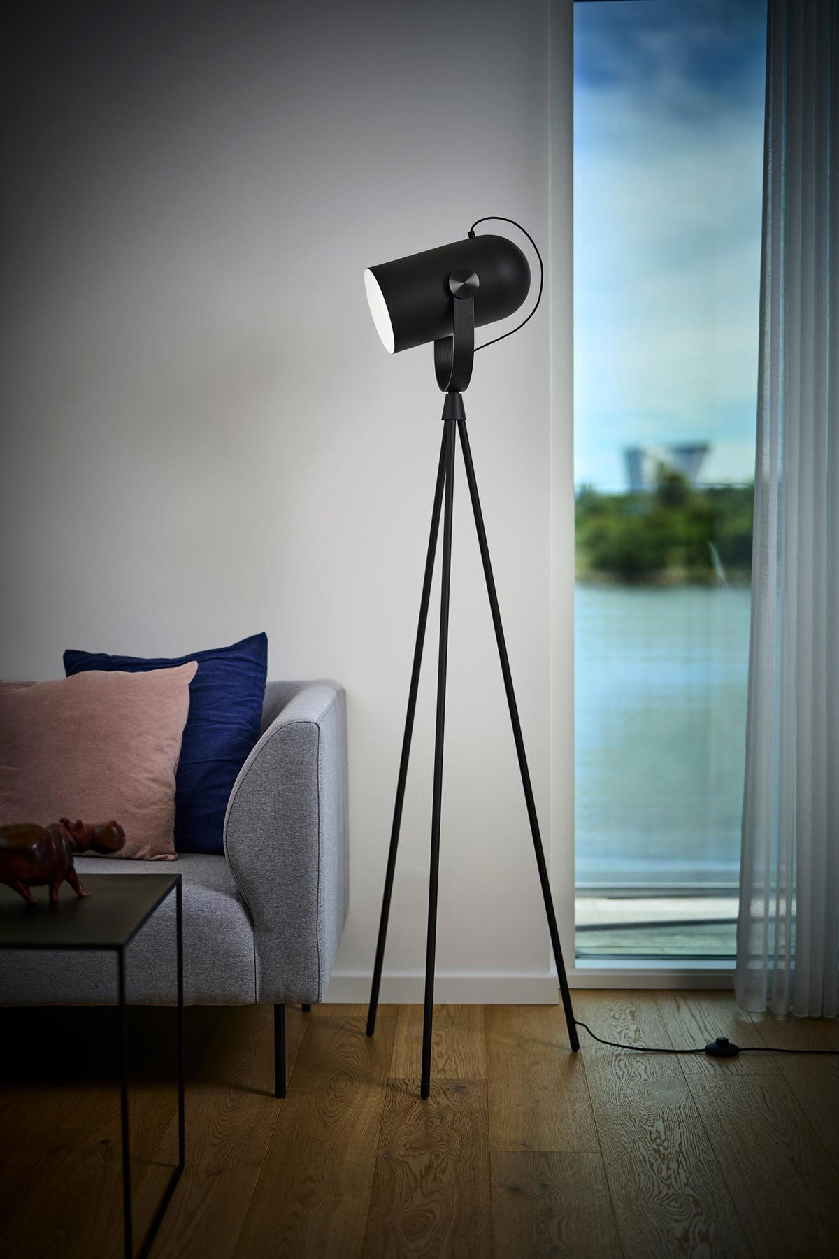 Carronade Golvlampa i svart ek med svart ståldetalj i dunkelt vardagsrum