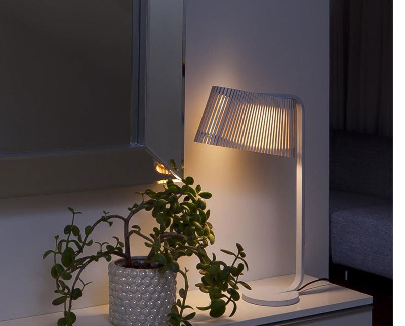 Owalo 7020 Bordslampa tänd i ett mörkt rum bredvid en krukväxt