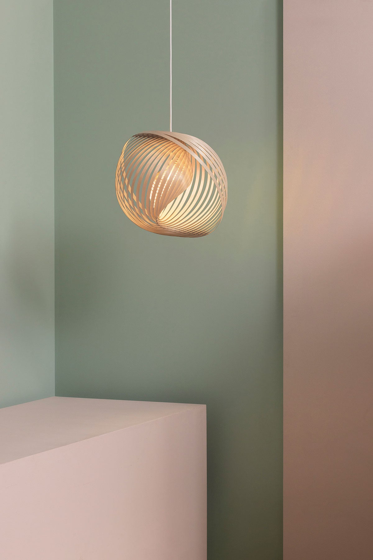 Adilo Small 8201 Taklampa i björk som hänger mot en ljusgrön och rosa vägg