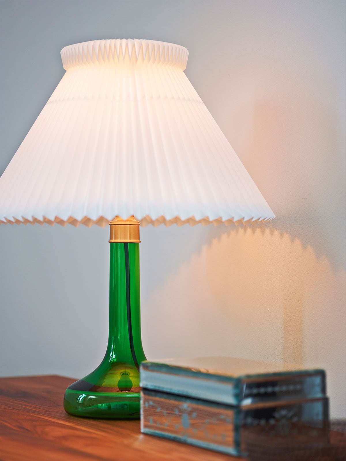 En tänd Le Klint 343 Bordslampa i färgen Green på skänk