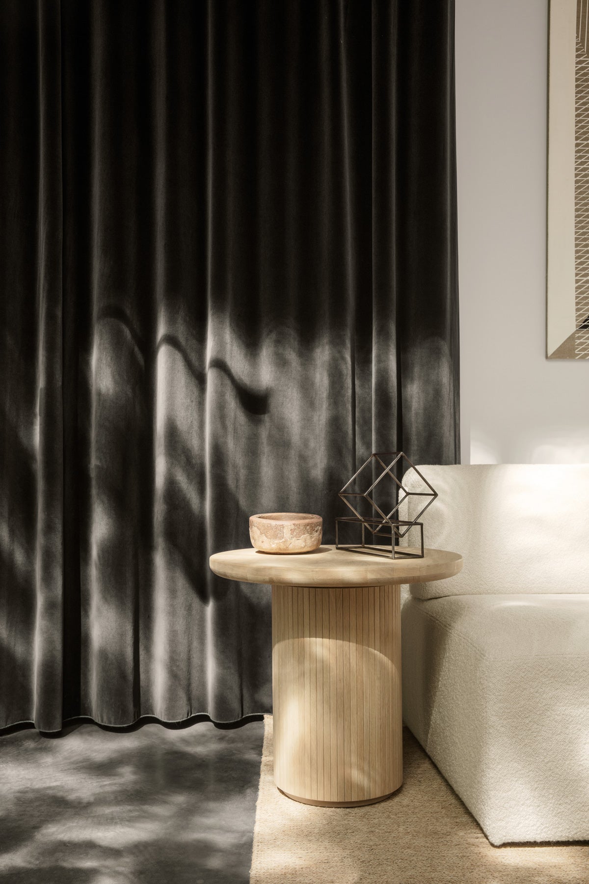 Moon Loungebord bredvid vit soffa med sammetsgardin i bakgrunden